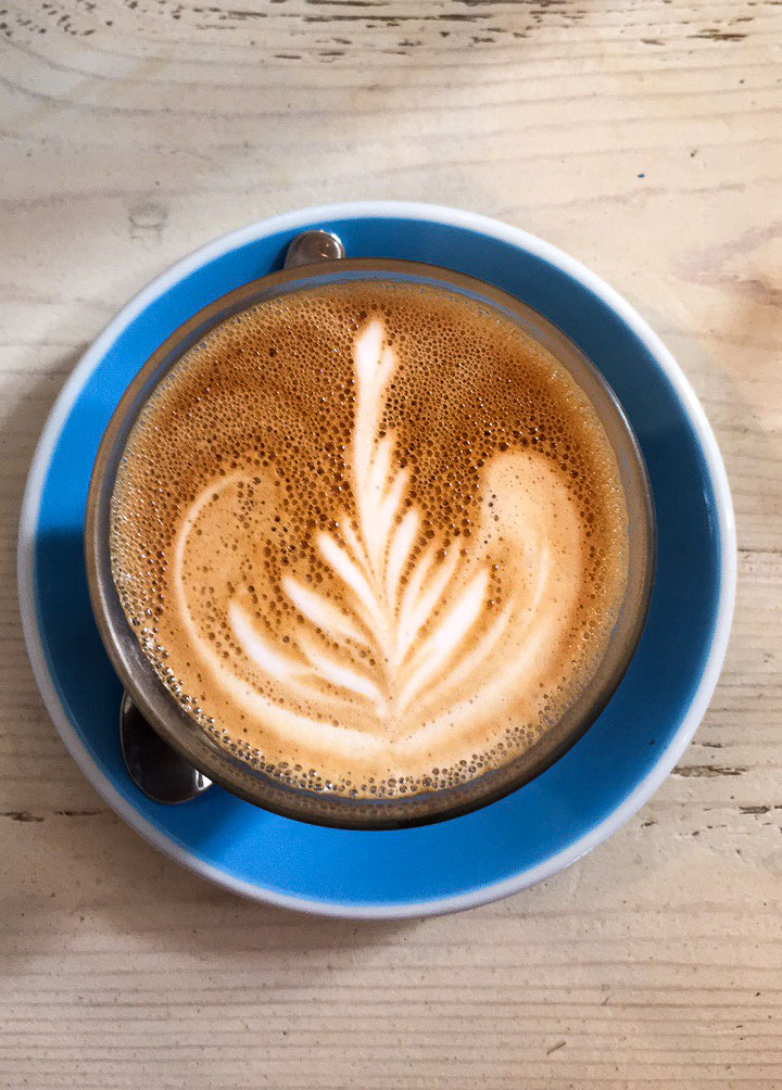 Coffee latte art with a blue plate and wooden background