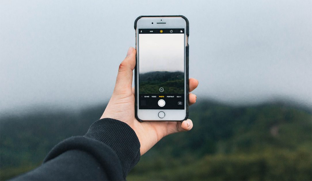 person holding phone open to camera app to take a picture of the out doors