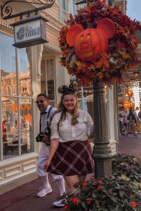 Girl posing next to Disney lampost with man photo bombing